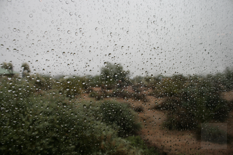 Rain drops on a window with the desert in the background.